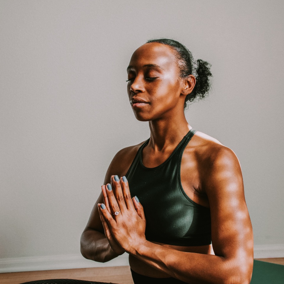Femme en méditation : Portrait d'une femme concentrée, les mains jointes en position de prière ou de méditation.