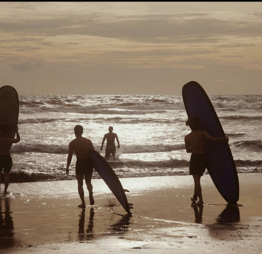 Promenade côtière : Des silhouettes marchant le long de l'eau sur une plage de sable humide.