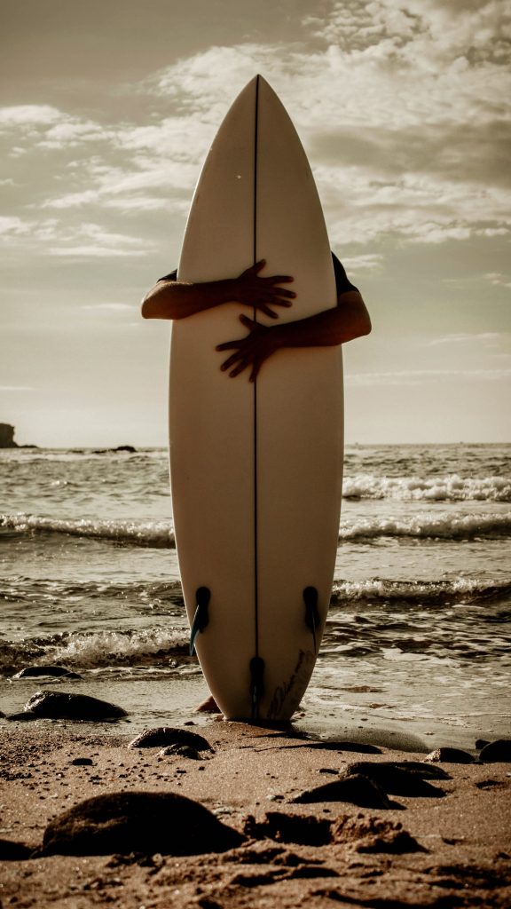 Personne tenant un skateboard en bord de plage