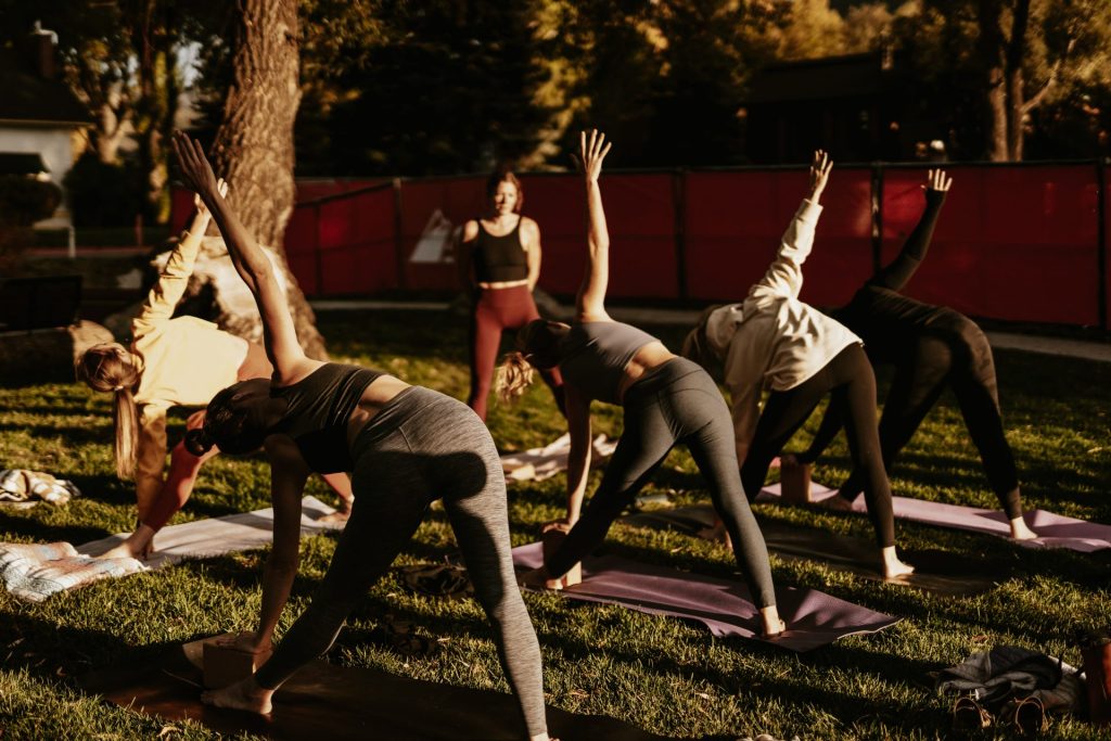 Cours de yoga : Un groupe de personnes pratiquant des postures de yoga en plein air sur des tapis.