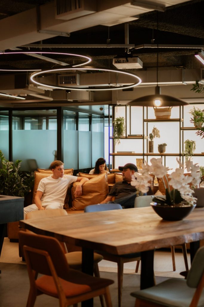 Réunion d'équipe : Un groupe de collaborateurs assis autour d'une table ronde en bois dans un bureau moderne et lumineux.