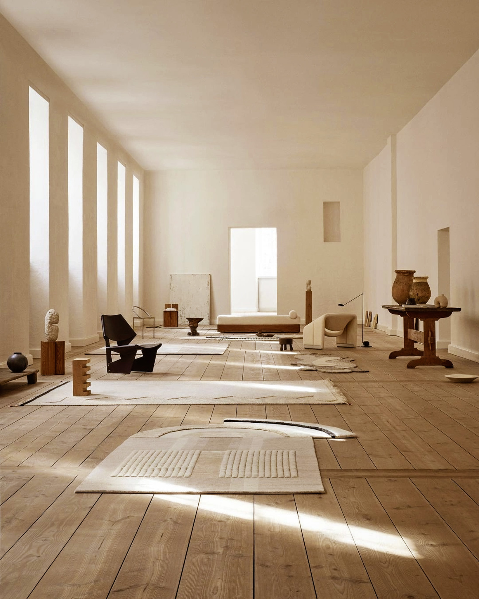 Studio lumineux : Un espace minimaliste et blanc baigné de lumière naturelle avec quelques tapis au sol.
